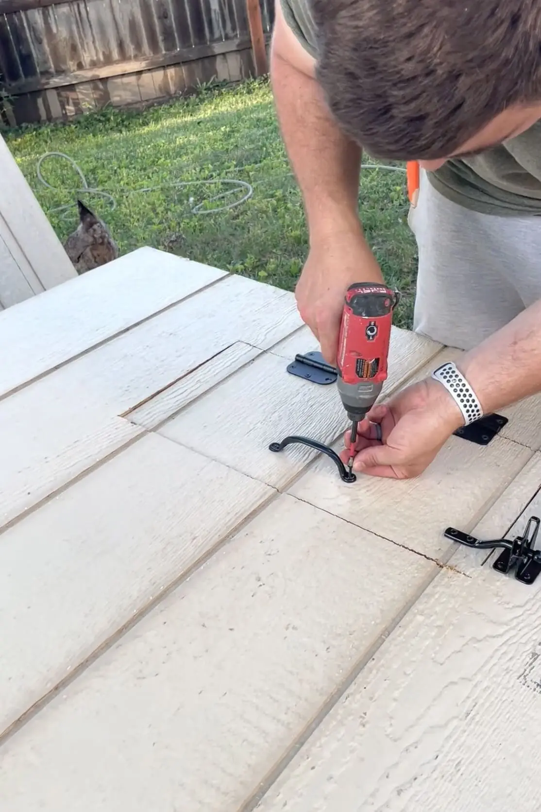 Adding hardware to a backyard DIY chicken coop.